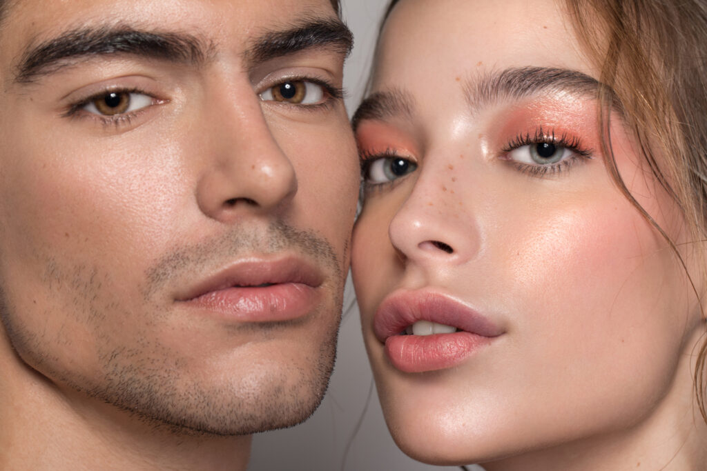 Closeup studio shot of a beautiful young woman and man with freckles skin posing against a grey background