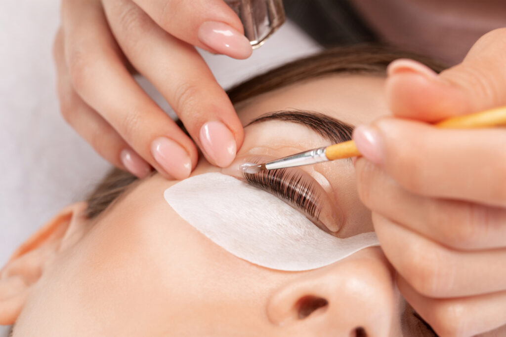 Make-up artist makes the procedure of lamination and dyeing of eyelashes to a beautiful woman in a beauty salon. Eyelash extensions. Eyelashes close-up